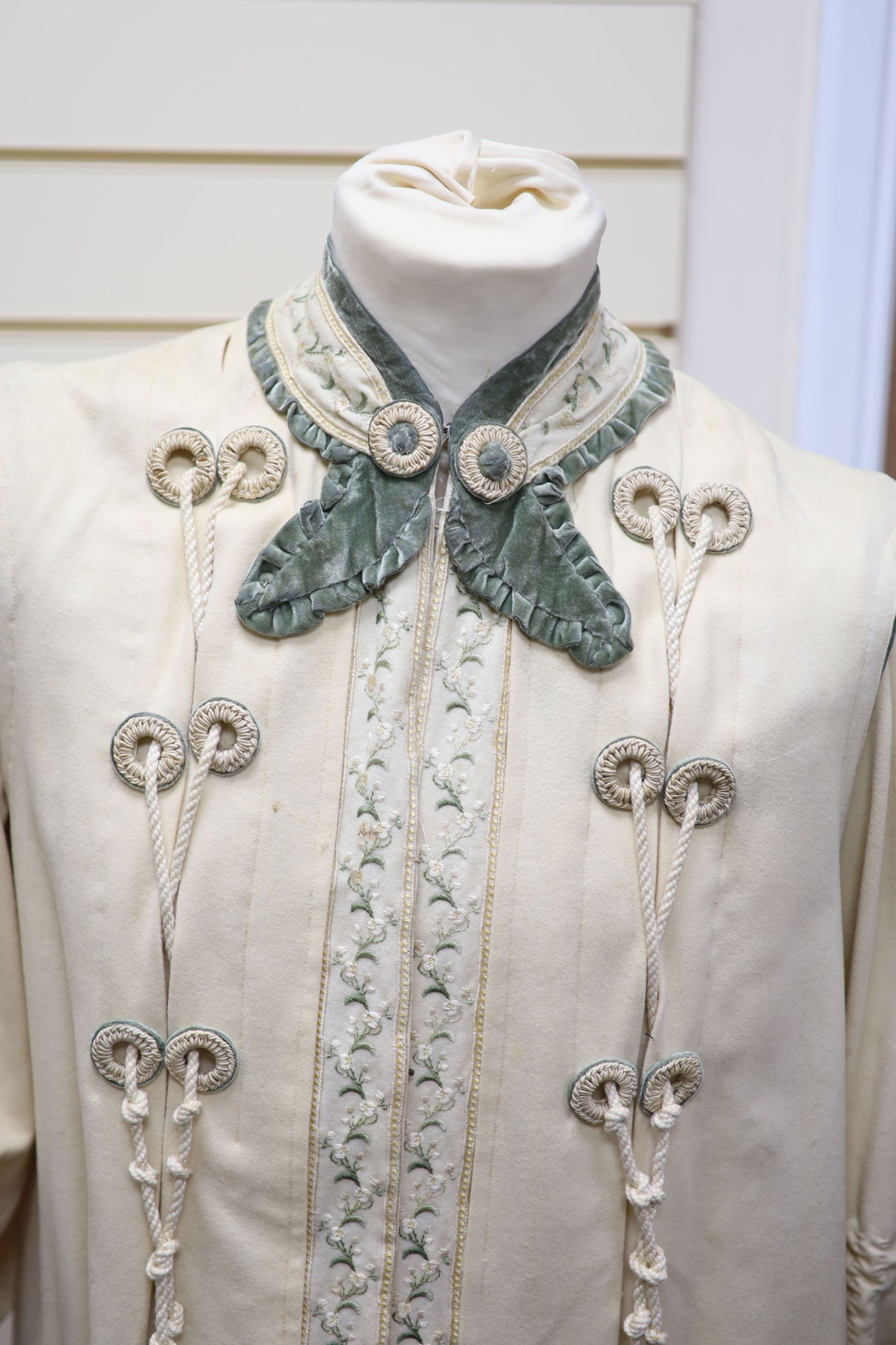 An Edwardian ladies fine cream wool coat with embroidered cuffs front edging and collar and ornate corded tasselling,